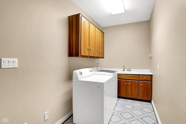 washroom with a sink, baseboards, cabinet space, light floors, and washer and clothes dryer