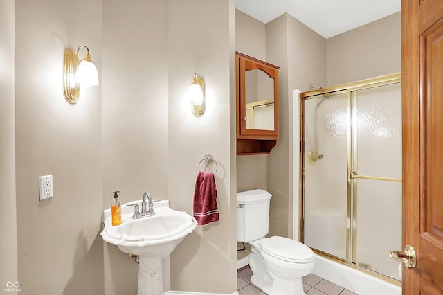 bathroom featuring tile patterned flooring, a shower with shower door, and toilet