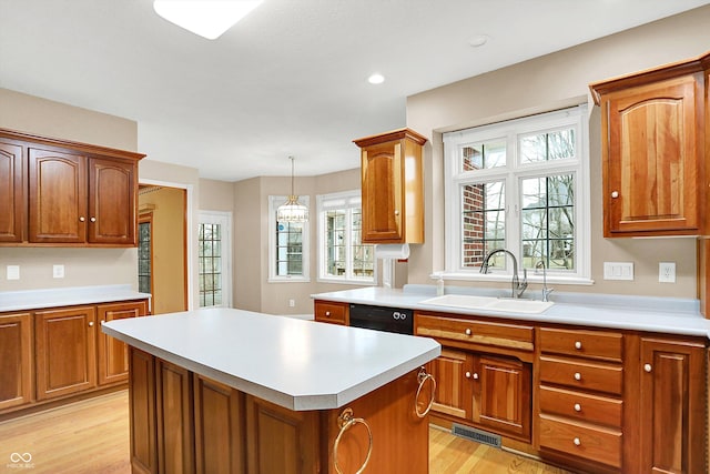 kitchen with pendant lighting, light countertops, a kitchen island, a sink, and dishwasher