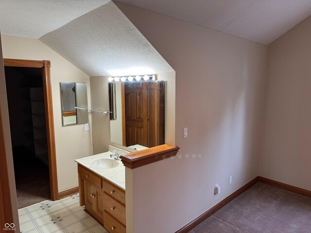 bathroom featuring lofted ceiling, baseboards, a textured ceiling, and vanity