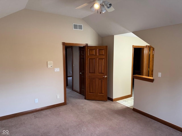 interior space with baseboards, visible vents, vaulted ceiling, and light colored carpet