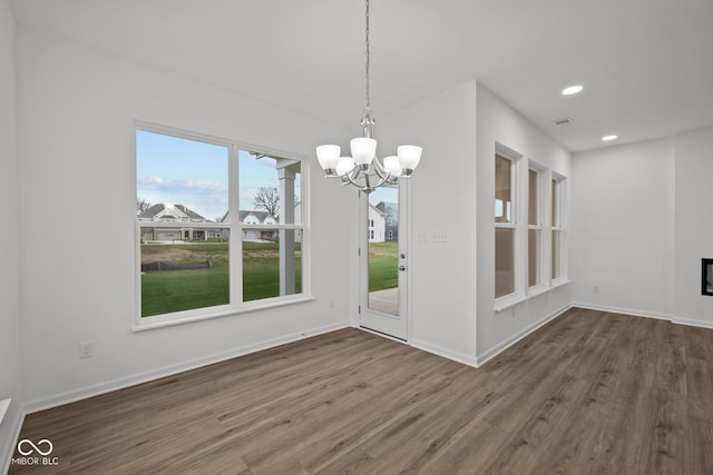 unfurnished dining area with hardwood / wood-style flooring and an inviting chandelier