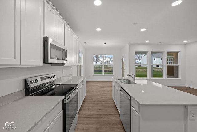 kitchen featuring sink, light wood-type flooring, stainless steel appliances, and an island with sink