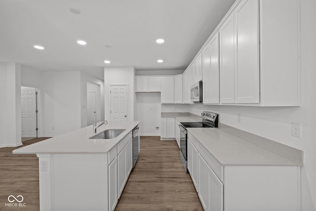 kitchen featuring white cabinetry, sink, a kitchen island with sink, appliances with stainless steel finishes, and light wood-type flooring