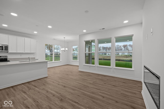 unfurnished living room featuring a chandelier, sink, and wood-type flooring