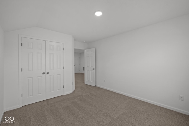 unfurnished bedroom with a closet, carpet floors, and lofted ceiling