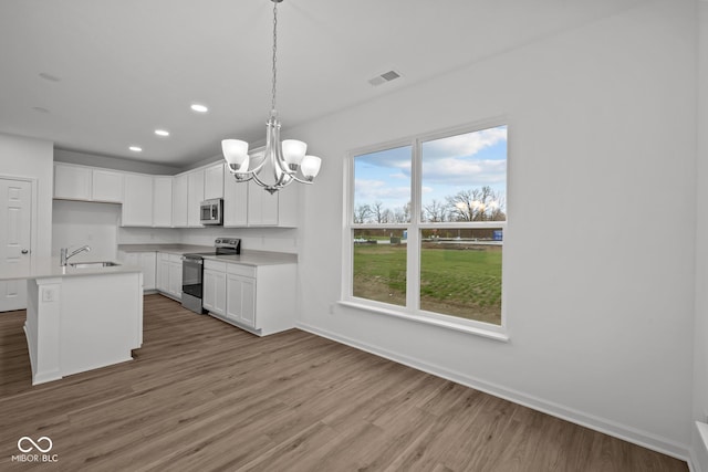 kitchen featuring a center island with sink, white cabinets, sink, hardwood / wood-style flooring, and appliances with stainless steel finishes