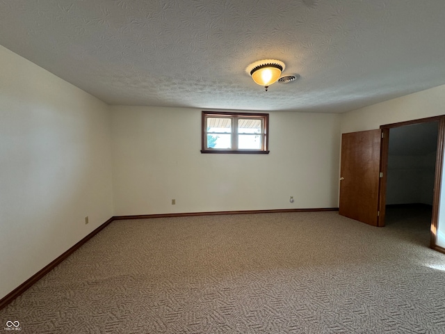 unfurnished room featuring a textured ceiling and light colored carpet