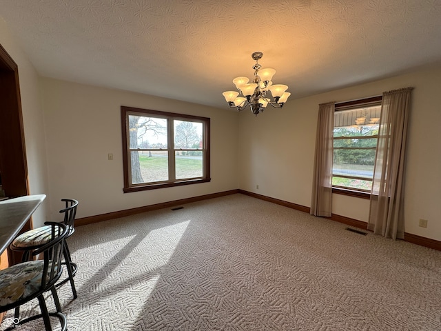 unfurnished dining area featuring carpet, a healthy amount of sunlight, and a textured ceiling