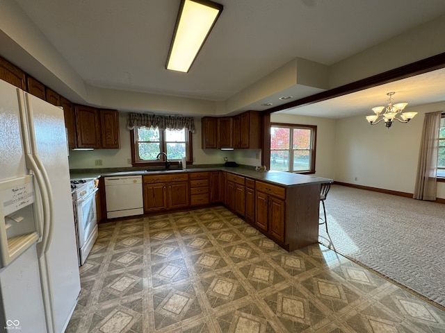 kitchen with kitchen peninsula, a healthy amount of sunlight, pendant lighting, and white appliances