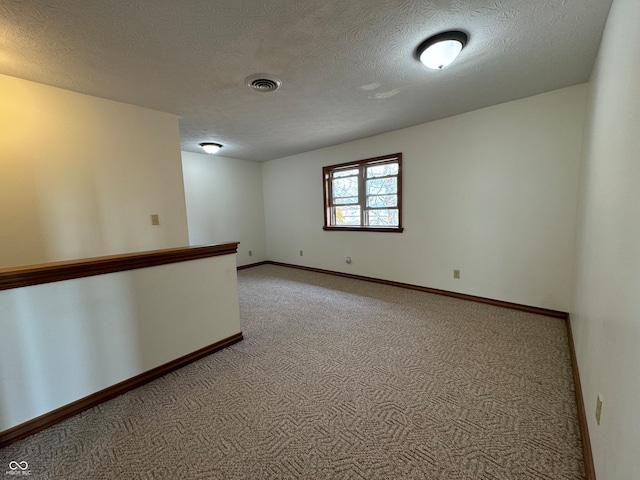 carpeted spare room with a textured ceiling