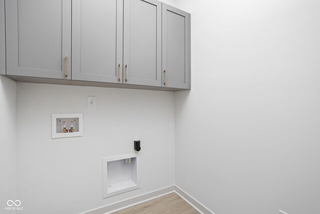 washroom featuring washer hookup, hookup for an electric dryer, cabinets, and light hardwood / wood-style floors