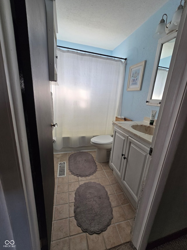 full bathroom featuring tile patterned floors, shower / bath combo, toilet, vanity, and a textured ceiling