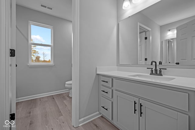 bathroom with hardwood / wood-style flooring, vanity, and toilet