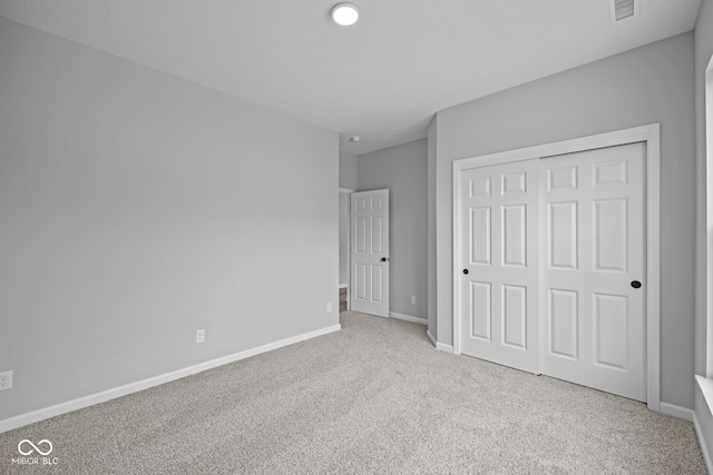 unfurnished bedroom with a closet and light colored carpet