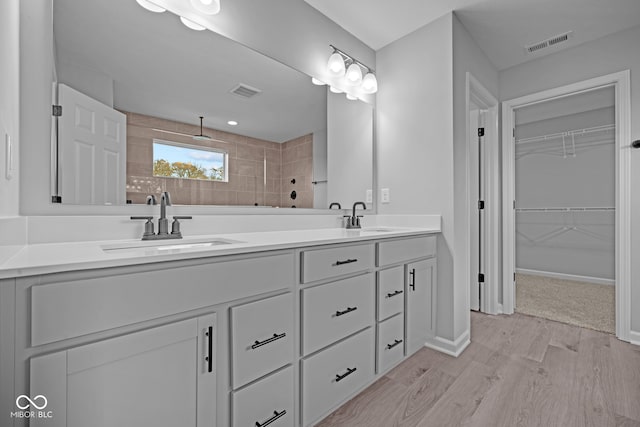 bathroom with vanity, wood-type flooring, and a tile shower