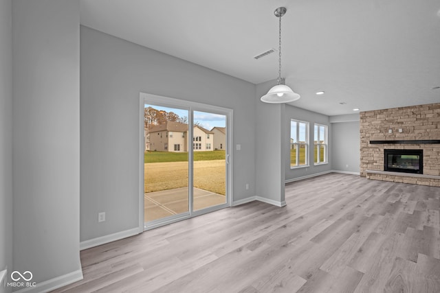 unfurnished living room featuring a wealth of natural light, light hardwood / wood-style floors, and a fireplace