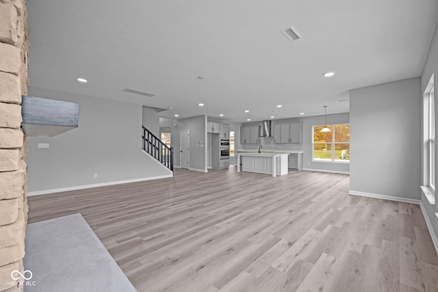 unfurnished living room with sink and light hardwood / wood-style flooring