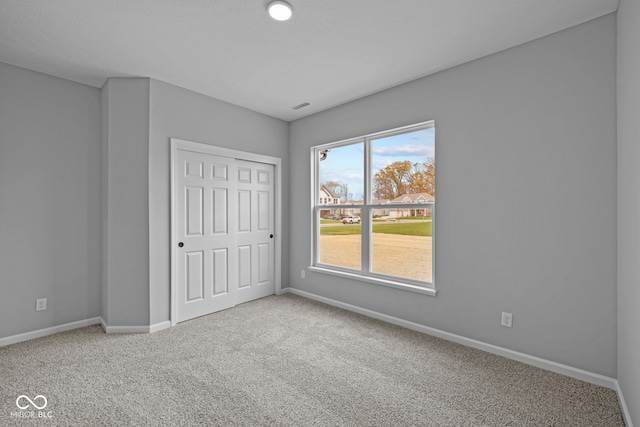 unfurnished bedroom featuring light carpet and a closet