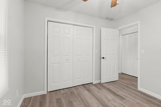 unfurnished bedroom with ceiling fan, a textured ceiling, and light wood-type flooring