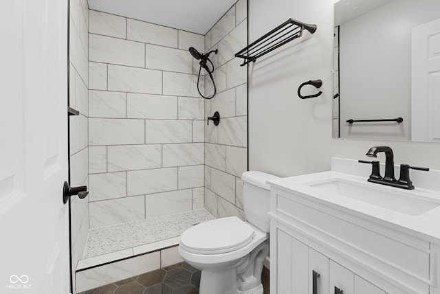 bathroom with tiled shower, vanity, and toilet