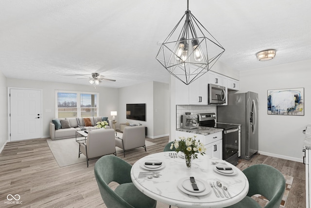 dining area with a textured ceiling, hardwood / wood-style floors, and ceiling fan with notable chandelier