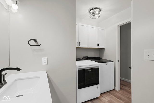 washroom with washer and dryer, sink, cabinets, and light hardwood / wood-style flooring