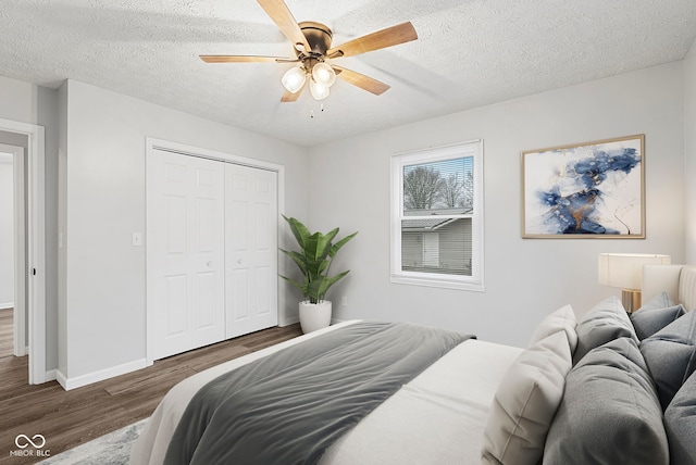 bedroom with ceiling fan, a closet, dark wood-type flooring, and a textured ceiling