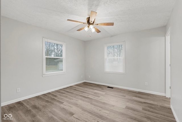 spare room with a textured ceiling, light hardwood / wood-style flooring, and ceiling fan