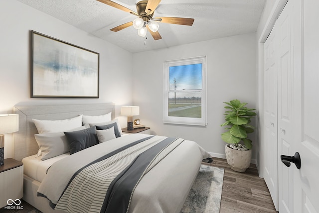 bedroom with hardwood / wood-style floors, ceiling fan, a textured ceiling, and a closet