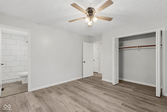 unfurnished bedroom with a textured ceiling, ceiling fan, hardwood / wood-style floors, connected bathroom, and a closet