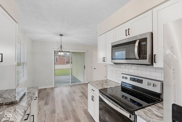 kitchen featuring light stone countertops, stainless steel appliances, white cabinetry, and tasteful backsplash