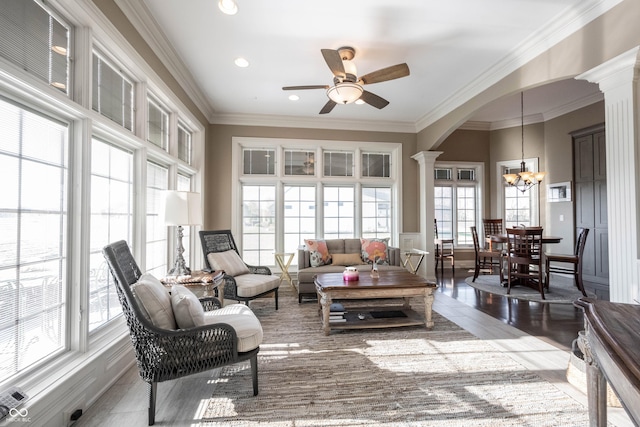 sunroom featuring ceiling fan with notable chandelier and ornate columns