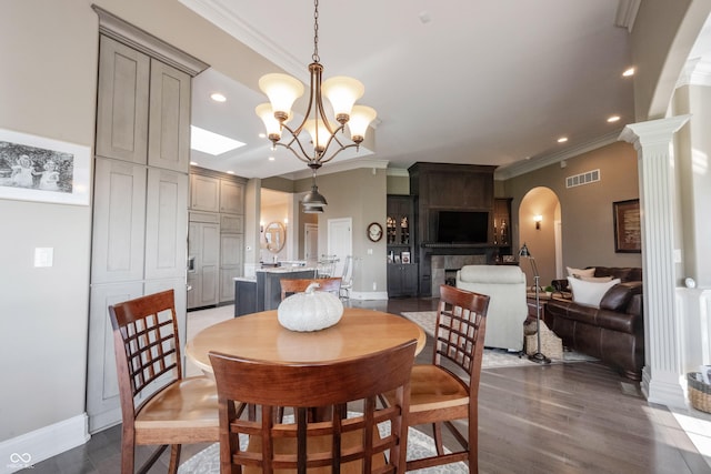 dining area featuring decorative columns, ornamental molding, dark hardwood / wood-style floors, and a chandelier