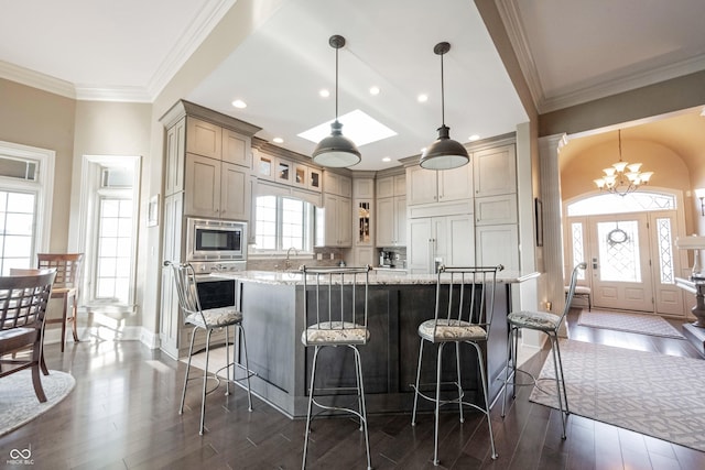 kitchen featuring built in appliances, light stone counters, decorative light fixtures, and a center island