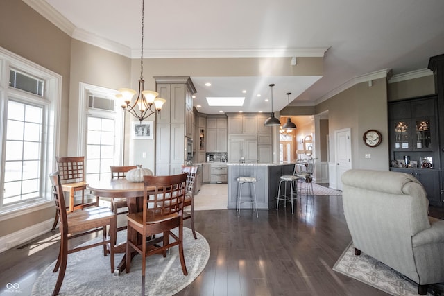 dining room with an inviting chandelier, crown molding, a skylight, and dark hardwood / wood-style floors