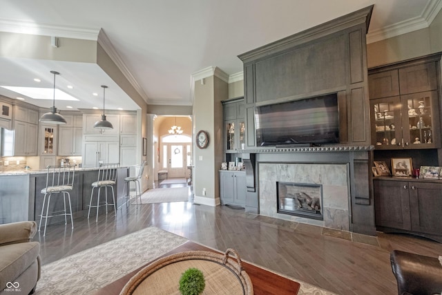 living room featuring dark hardwood / wood-style floors, a fireplace, ornamental molding, a notable chandelier, and built in shelves