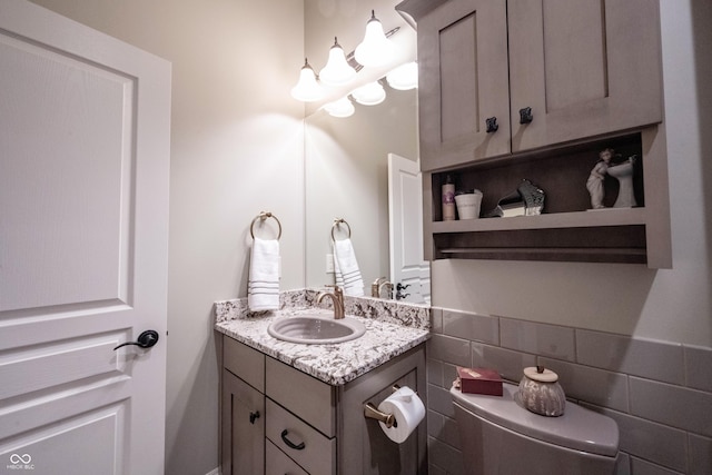 bathroom featuring vanity, toilet, and tile walls