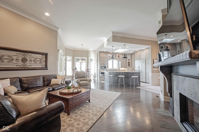 living room featuring a premium fireplace, crown molding, a chandelier, and dark hardwood / wood-style flooring