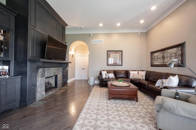 living room with crown molding, wood-type flooring, and a fireplace