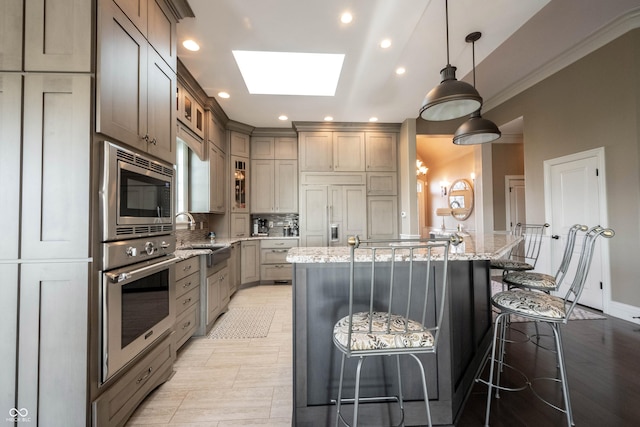 kitchen featuring a kitchen island, a skylight, a kitchen bar, built in appliances, and light stone countertops