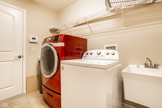 clothes washing area with independent washer and dryer and sink