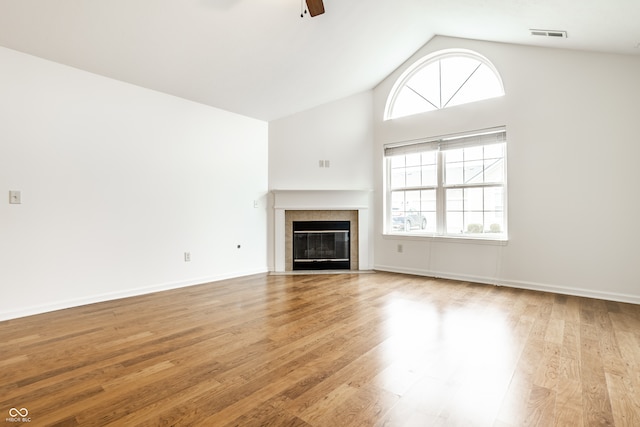 unfurnished living room featuring a tile fireplace, ceiling fan, lofted ceiling, and light wood-type flooring