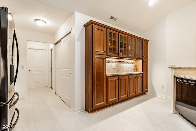 interior space featuring light stone countertops, dishwasher, tasteful backsplash, stainless steel fridge, and light tile patterned floors