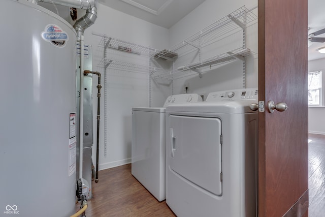 laundry room with wood-type flooring, water heater, and washing machine and clothes dryer