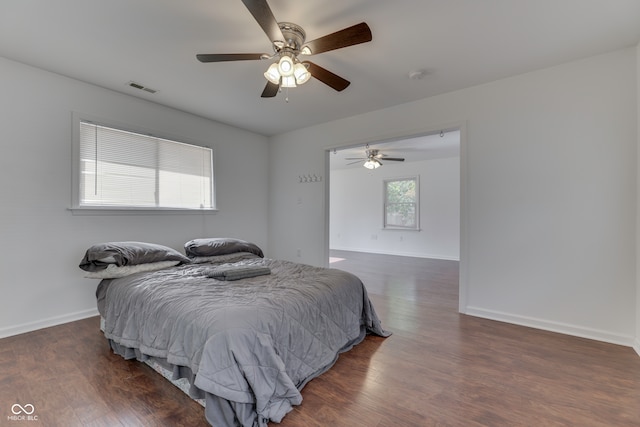 bedroom with multiple windows, dark hardwood / wood-style floors, and ceiling fan