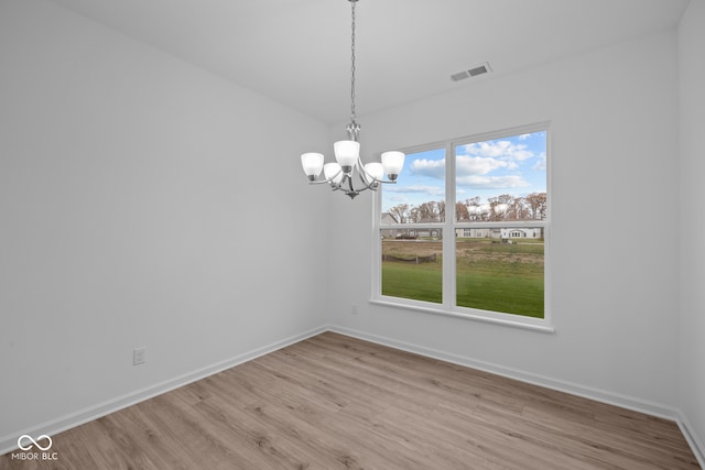 unfurnished dining area with a notable chandelier and light hardwood / wood-style flooring