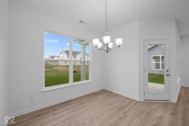 unfurnished dining area with light wood-type flooring and a chandelier