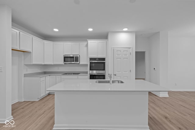 kitchen with stainless steel appliances, sink, a center island with sink, light hardwood / wood-style flooring, and white cabinets