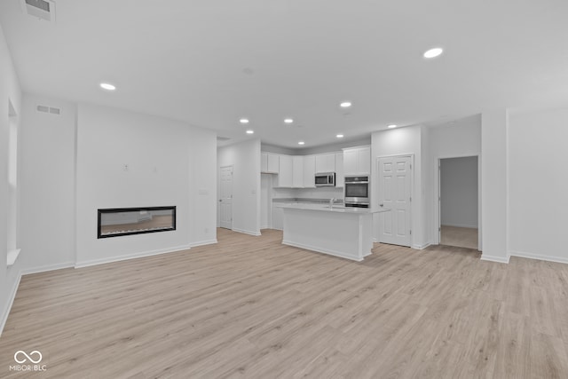 unfurnished living room featuring sink and light wood-type flooring